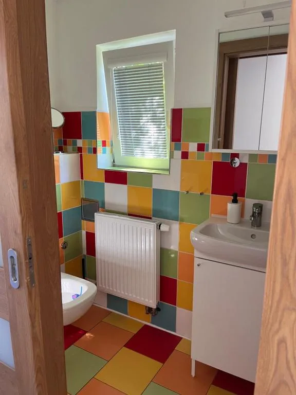 Koupelna apartmánu 3 s barevným obkladem a umyvadlem