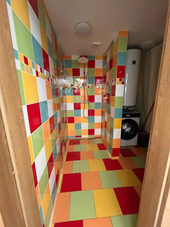 Sprchový kout apartmánu 3 s barevným obkladem a pračkou